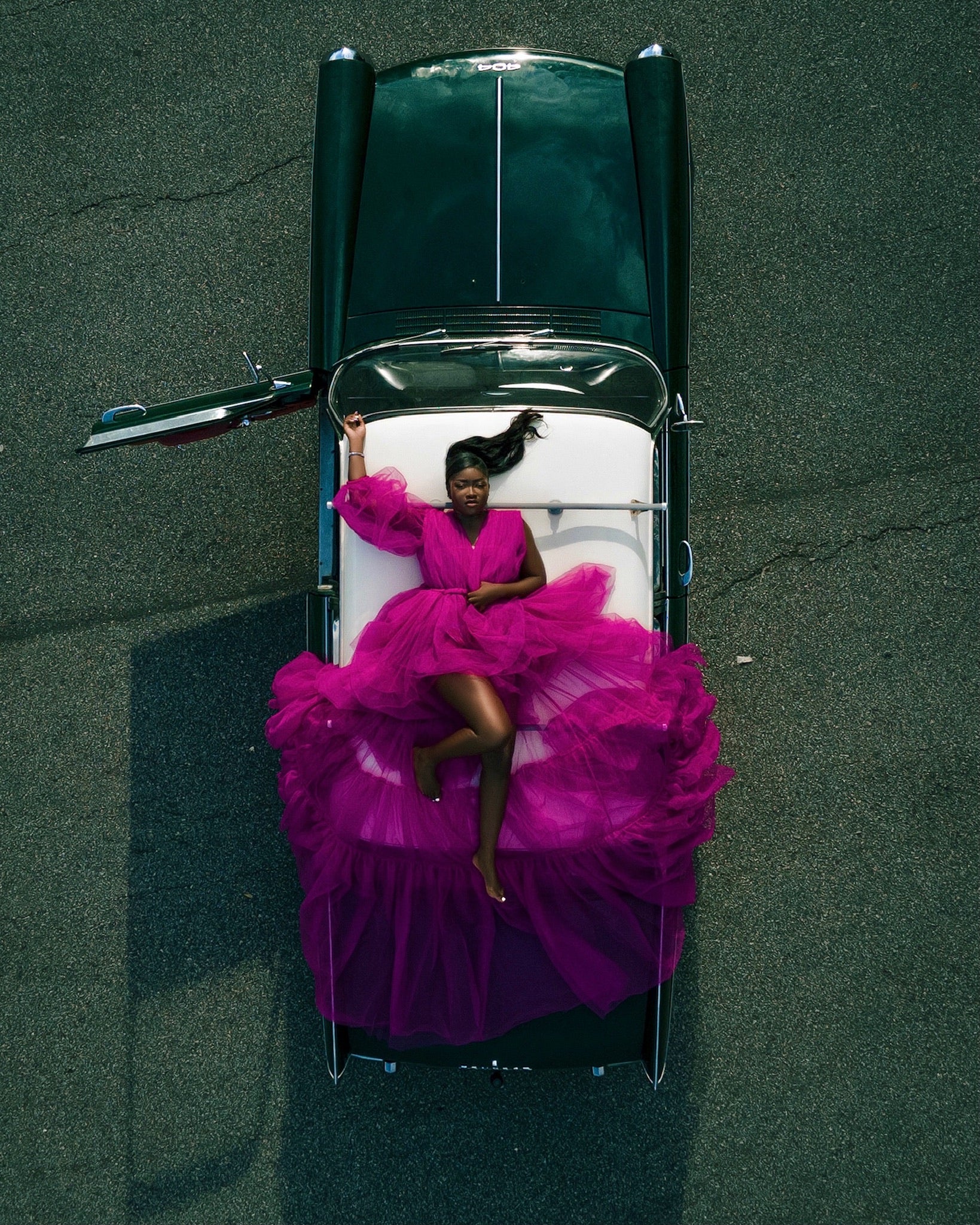 Girl lying down on a vintage car wearing a fluffy dress by dimaz